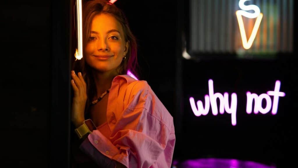 Smiling teenager in a studio with neon lights and ice cream sign, vibrant youth culture.