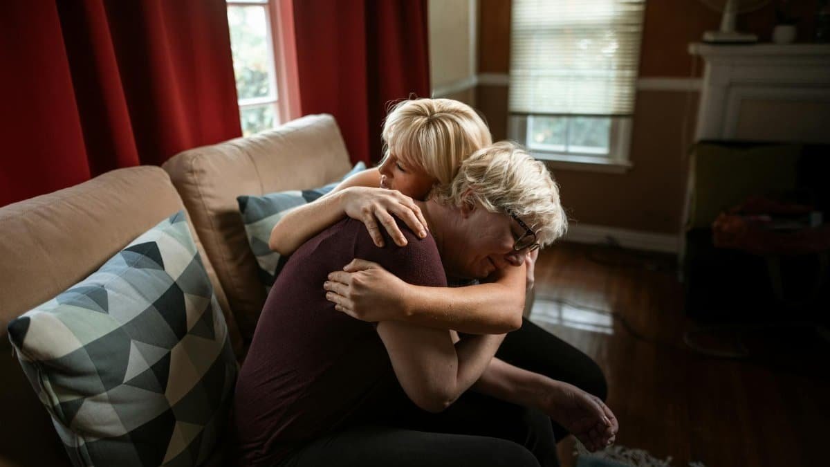 An emotional and supportive embrace between a couple on a sofa, showcasing affection and togetherness in a cozy home setting.