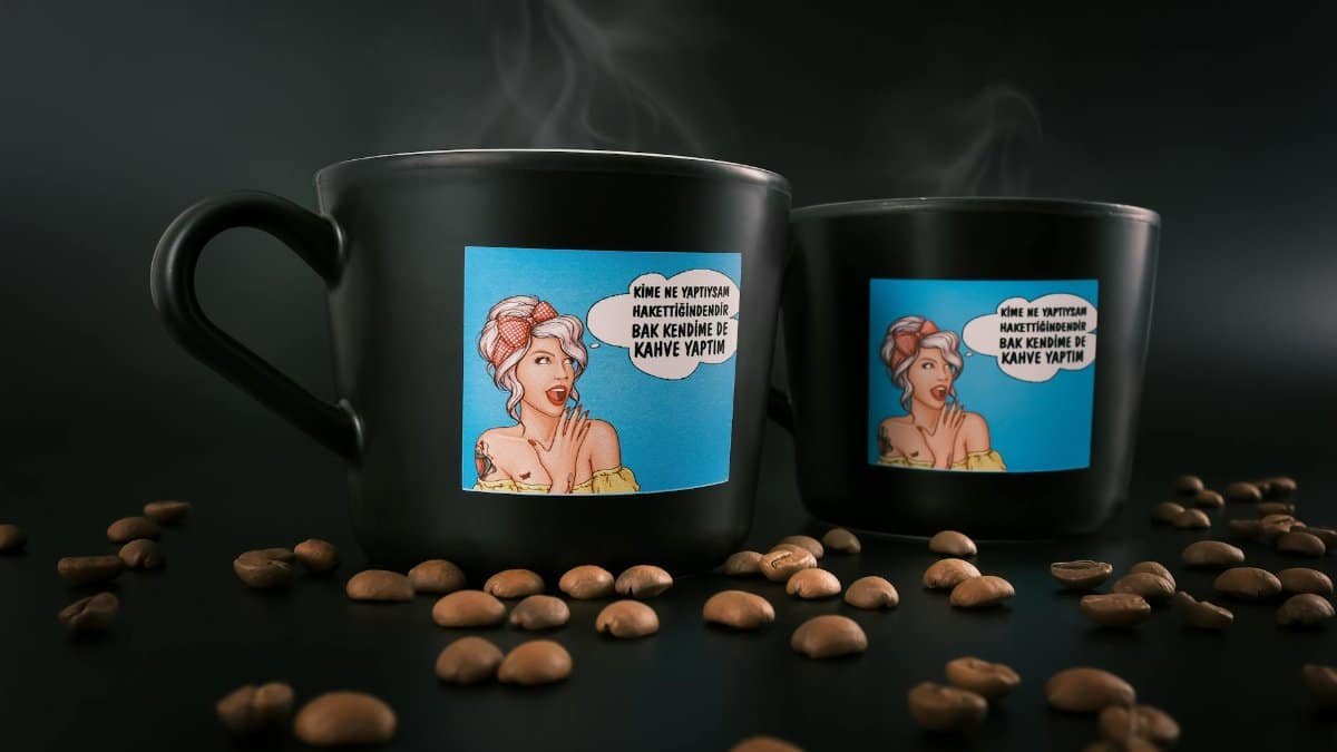 Black coffee mugs with a vibrant cartoon design surrounded by coffee beans. Perfect for coffee lovers.