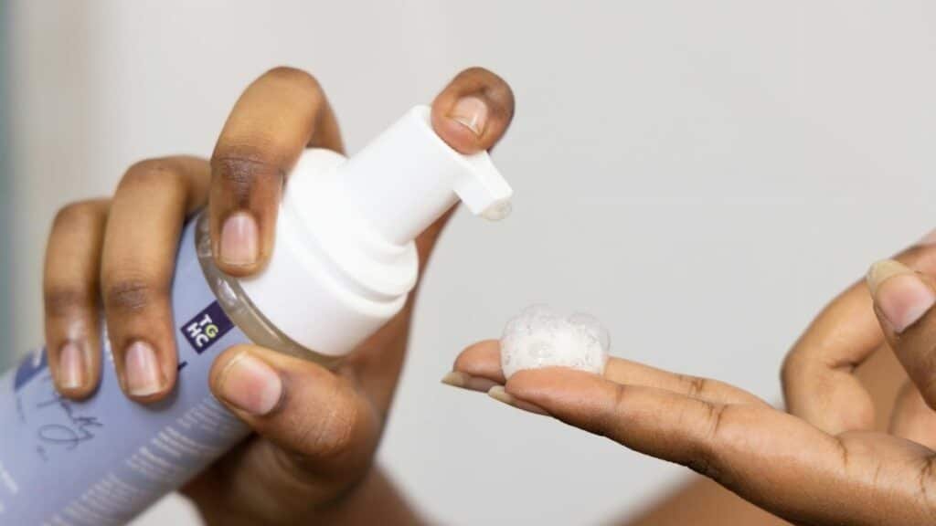 Close-up of hands dispensing soothing foaming face wash, ideal for sensitive skin care.