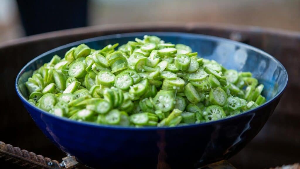 A close-up view of sliced okra in a blue bowl, perfect for cooking inspiration.