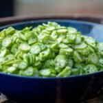 A close-up view of sliced okra in a blue bowl, perfect for cooking inspiration.