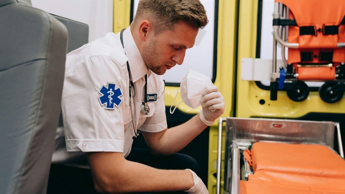 Paramedic in uniform preparing equipment inside an ambulance, emphasizing readiness and professionalism.