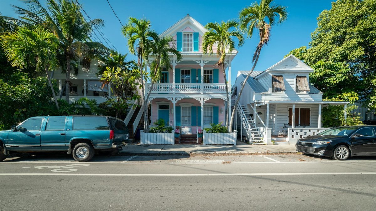 Colorful historic houses with palm trees along a sunny street in Key West, Florida.