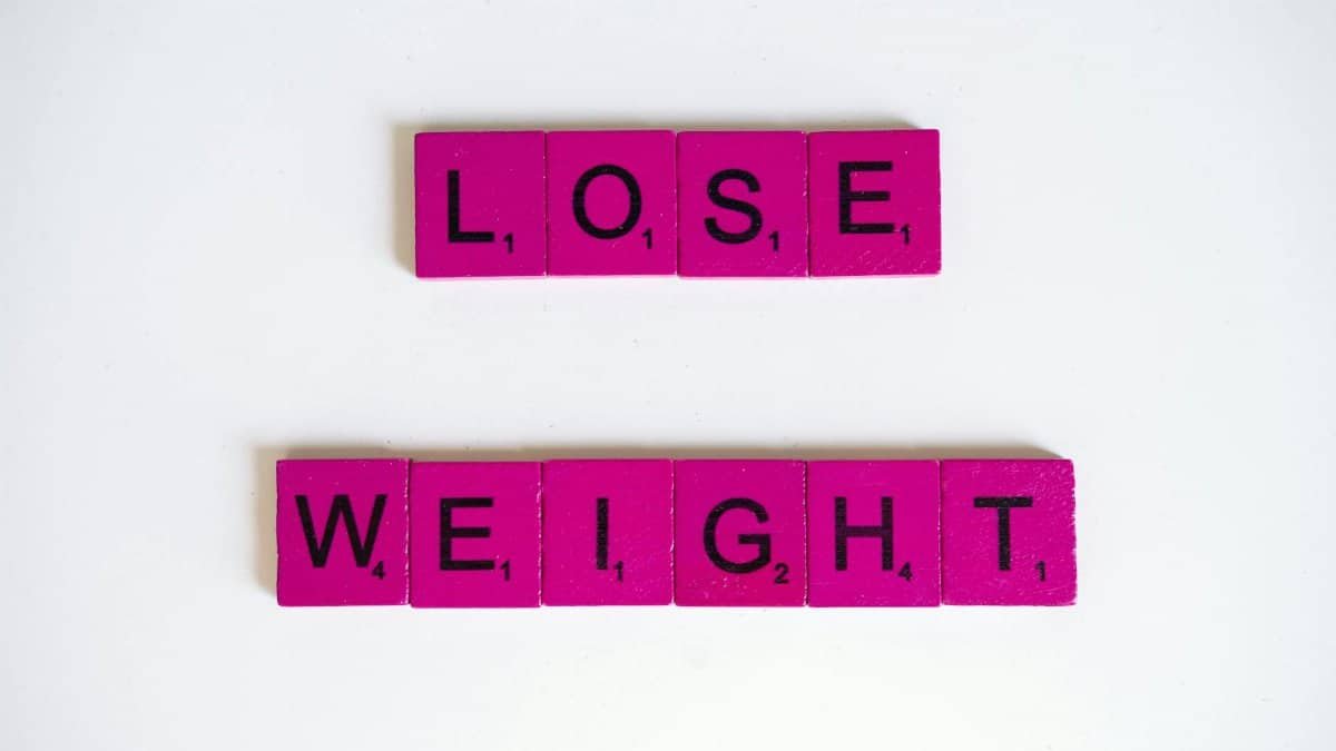 Creative image of the phrase 'Lose Weight' spelled with Scrabble tiles on a white background.