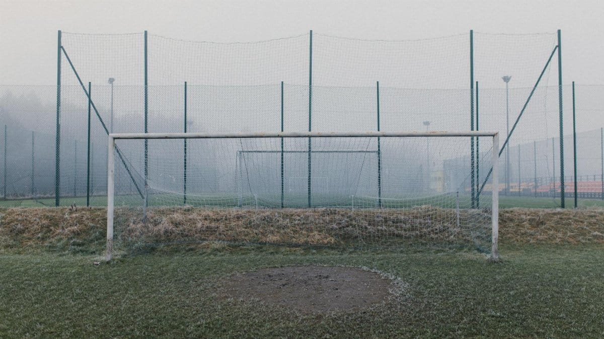 Misty football field featuring a frosty goal post and fog enveloping the sports ground.