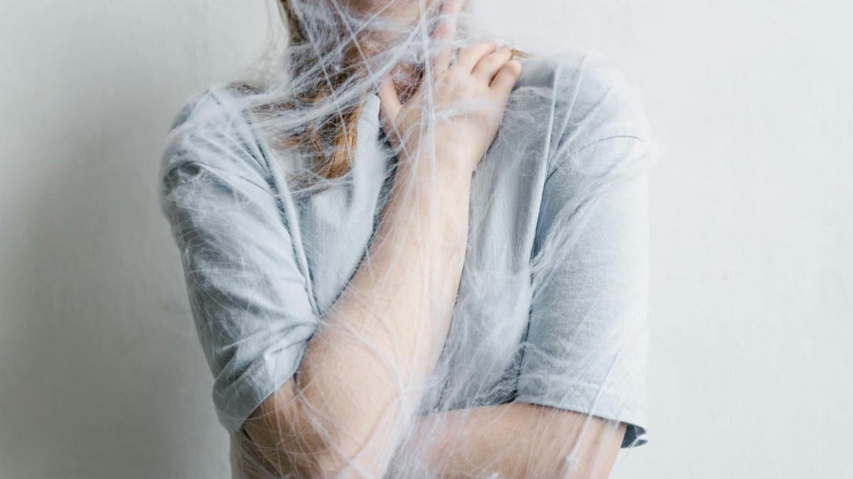 A woman metaphorically trapped in a spider web depicting anxiety and entrapment.