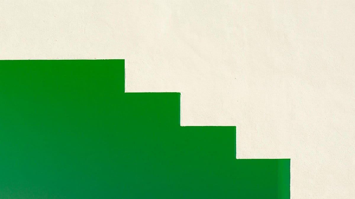 Minimalist design featuring a green staircase against a white wall, creating stark contrast.