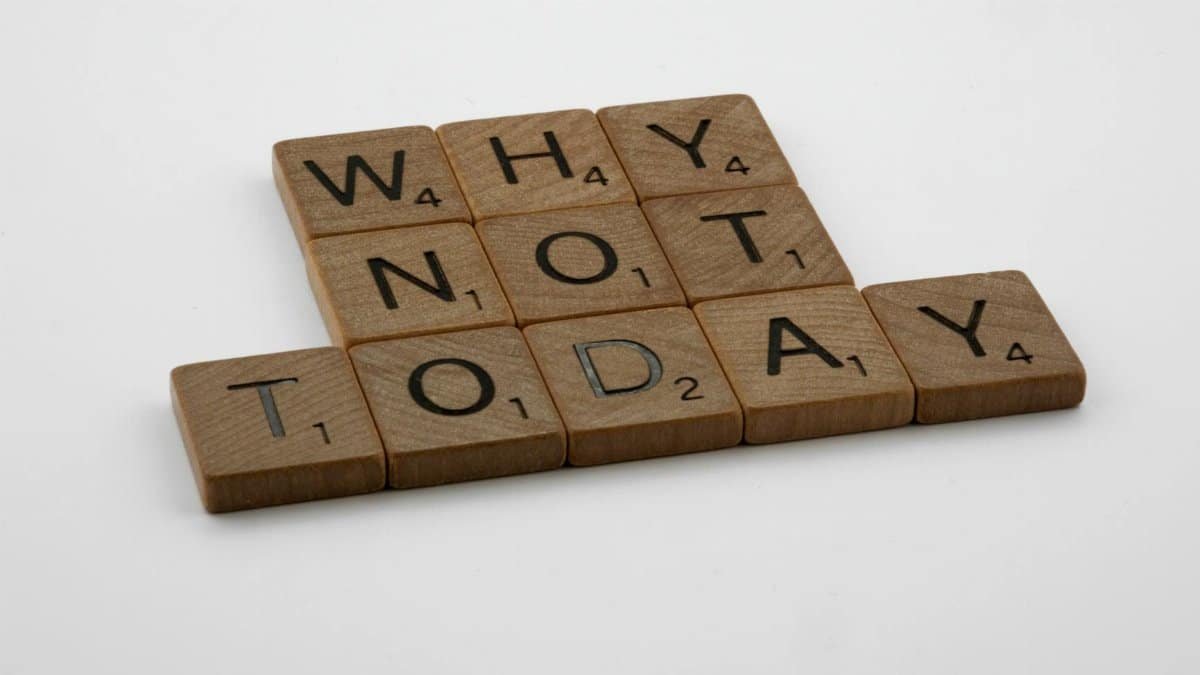 Wooden scrabble tiles arranged to form a motivational message on a white background.