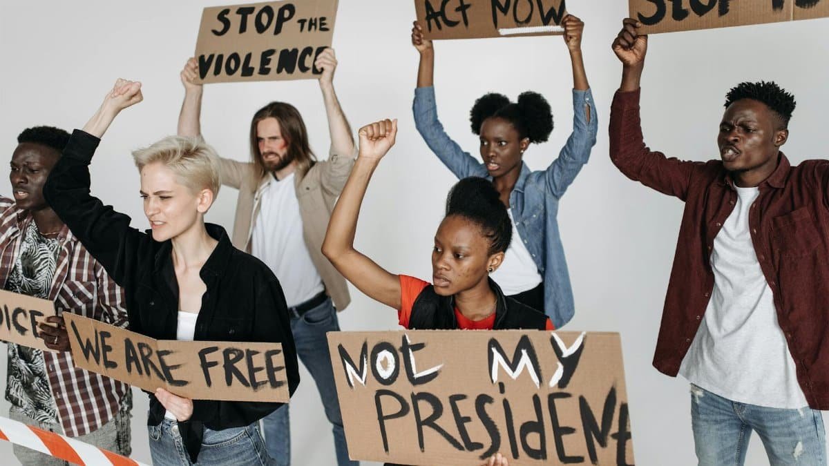 A diverse group of activists holding protest signs in a studio setting, advocating for human rights and justice.