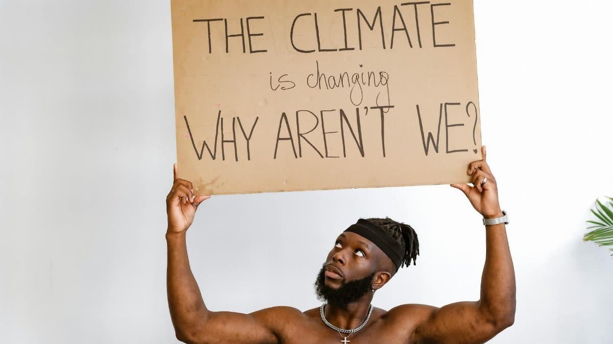 Shirtless African American man holding a climate change awareness sign.