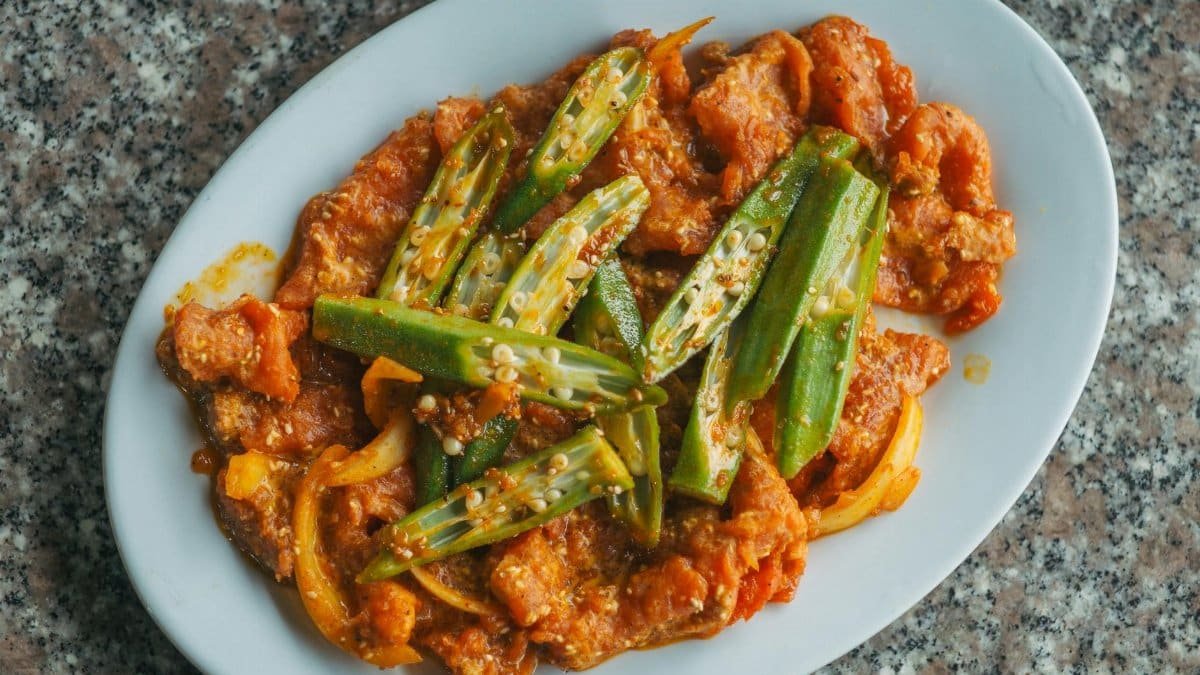 A vibrant dish featuring cooked okra, tender chicken, and a rich tomato sauce, perfect for food photography.