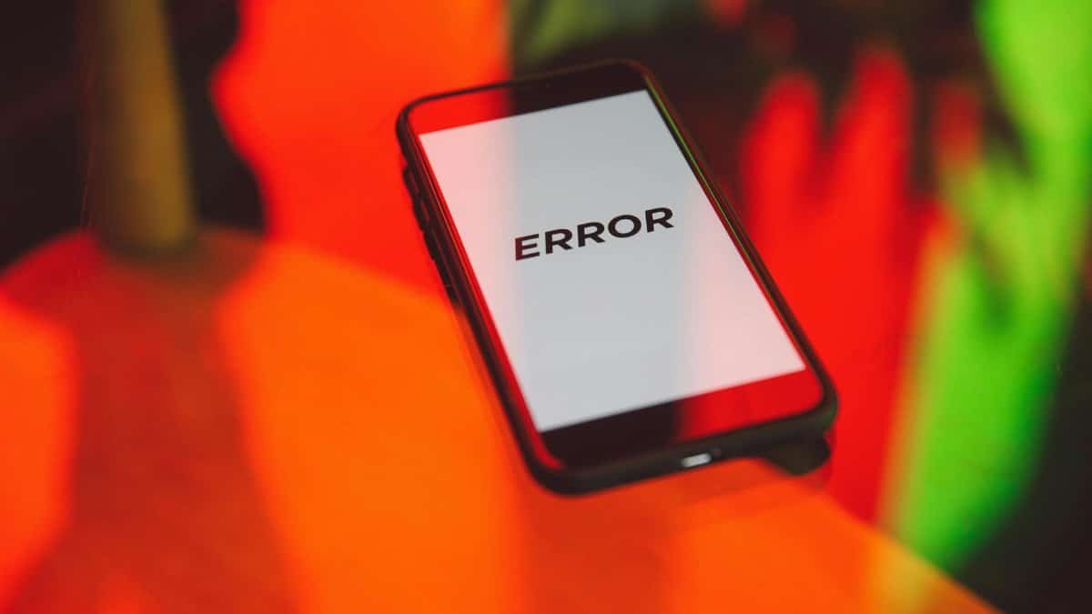A smartphone displaying an 'ERROR' message surrounded by vibrant red and green reflections indoors.