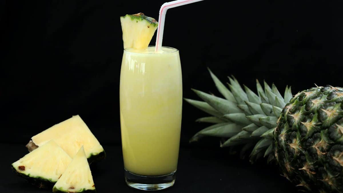 A tropical glass of fresh pineapple juice garnished with a slice and straw, perfect for summer refreshment.