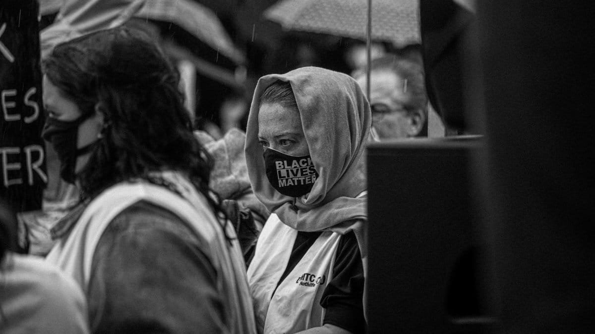Protesters with masks gather at a Black Lives Matter rally during rain.