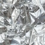 Close-up of a crumpled silver aluminum foil texture, perfect for creative backgrounds.