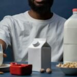Close-up of a man with almond milk options and nuts on a table, promoting a healthy lifestyle.