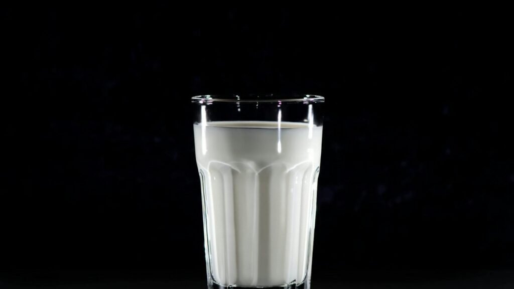A glass of fresh milk against a black background, emphasizing simplicity and nutrition.