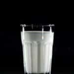 A glass of fresh milk against a black background, emphasizing simplicity and nutrition.