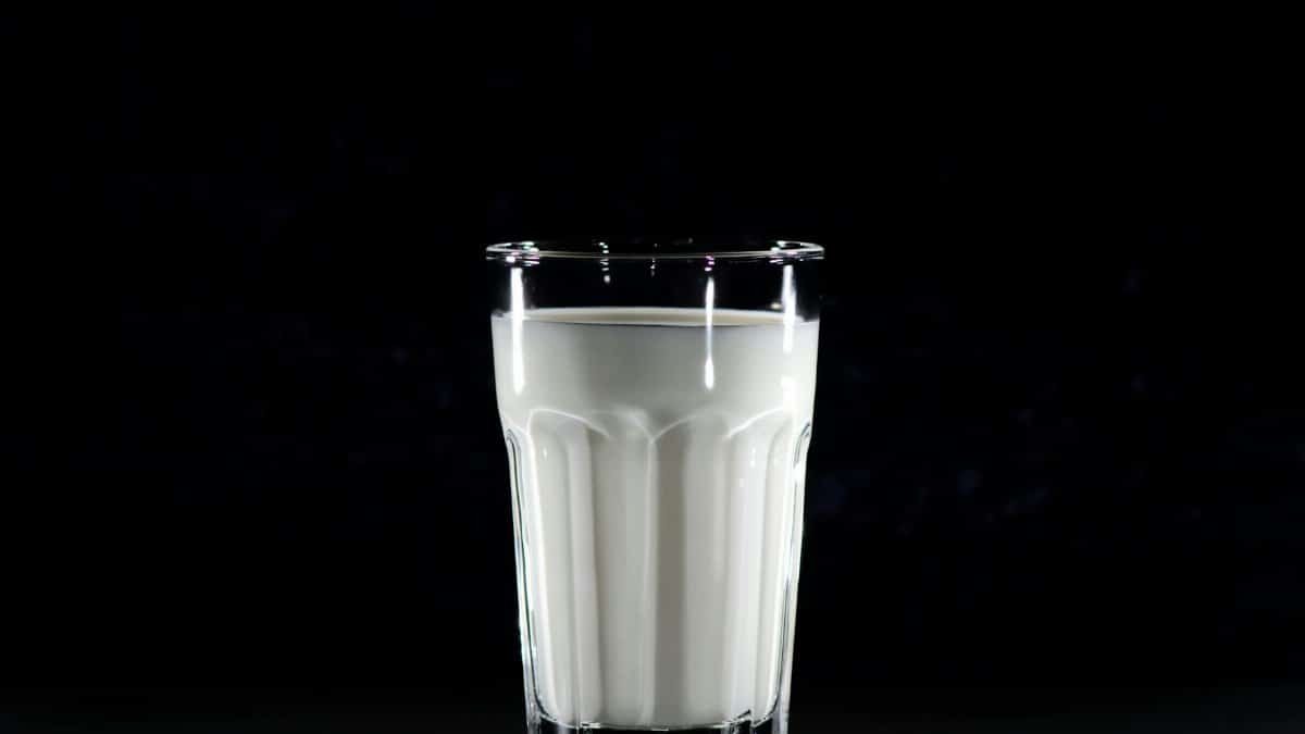 A glass of fresh milk against a black background, emphasizing simplicity and nutrition.