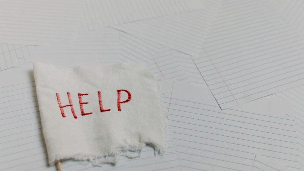 A flag with 'HELP' text on a lined paper background signifying distress or need for assistance.