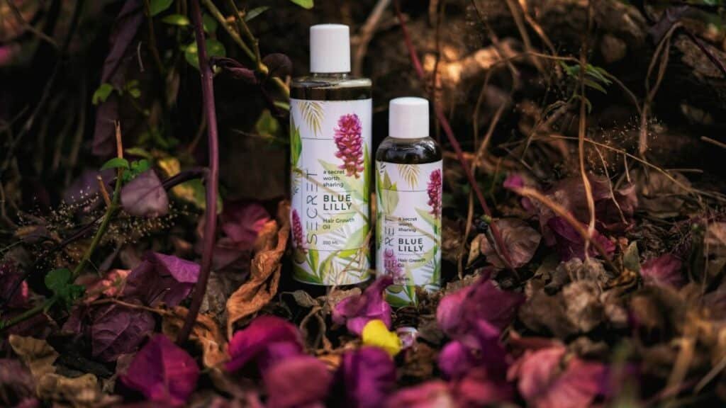 Herbal hair growth oils displayed among vibrant leaves in a forest setting.