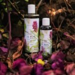 Herbal hair growth oils displayed among vibrant leaves in a forest setting.