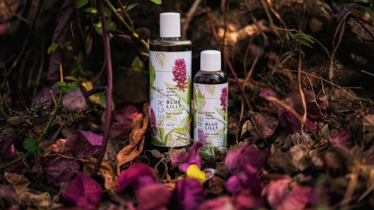 Herbal hair growth oils displayed among vibrant leaves in a forest setting.