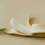 A peeled banana displayed on a soft beige background in a minimalist style.