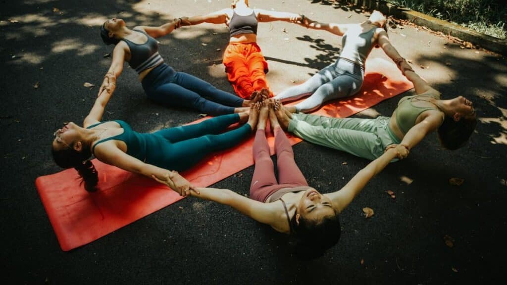 A group of women performing yoga outdoors in a circle, showcasing unity and fitness.