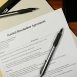 Flat lay of a marital dissolution agreement form with pens and files on a desk.