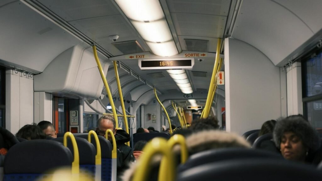 Passengers commuting inside a modern public train during the day.