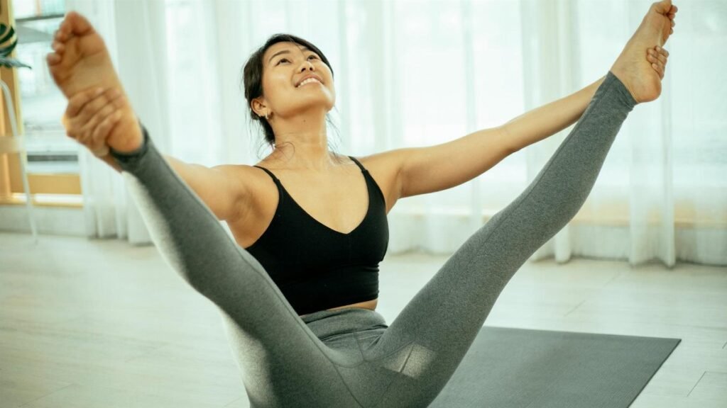 A woman practicing a yoga pose indoors on a mat, focusing on health and well-being.