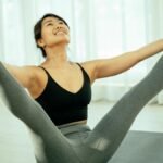 A woman practicing a yoga pose indoors on a mat, focusing on health and well-being.