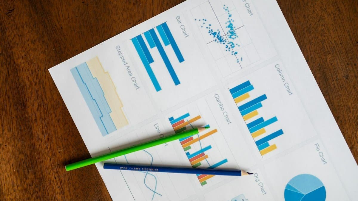 Top view of vibrant charts and colored pencils on wooden surface.