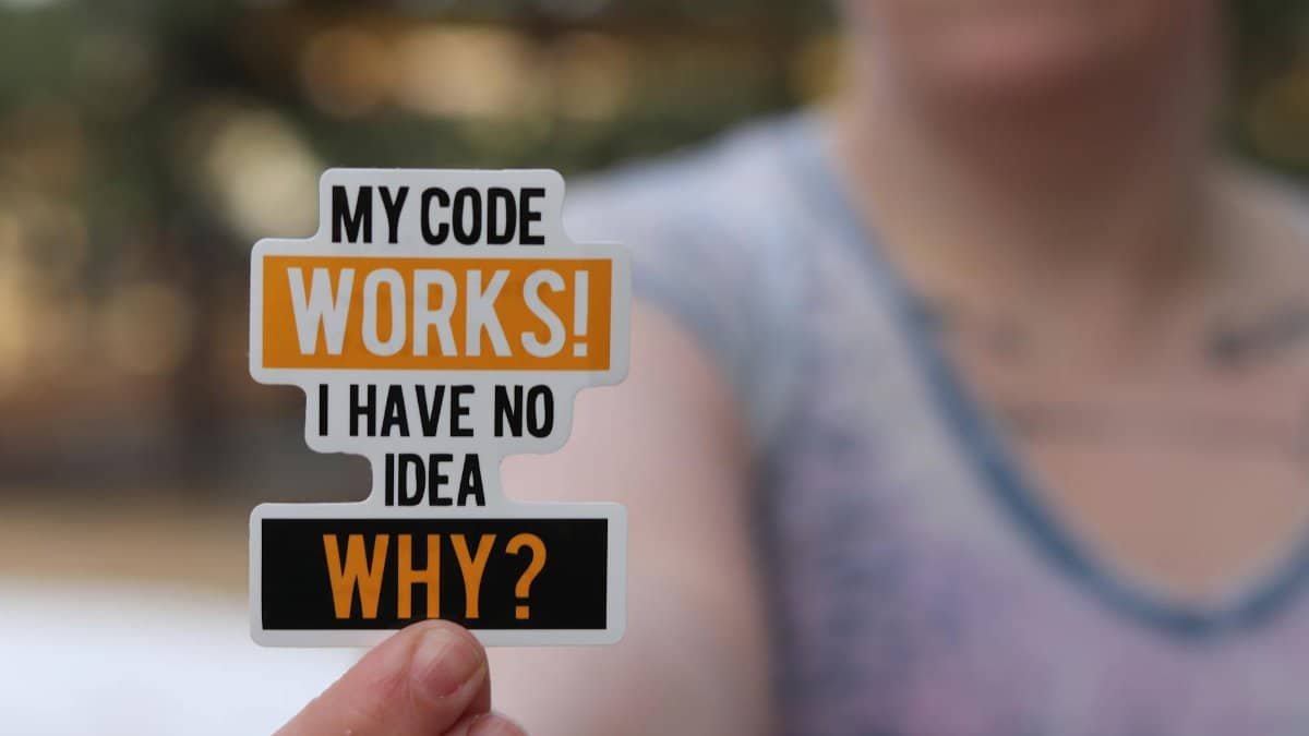 A close-up of a hand holding a humorous programming sticker perfect for tech enthusiasts.