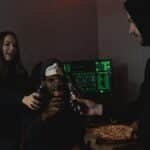 Group of hackers celebrating a successful hack with pizza and soda indoors.