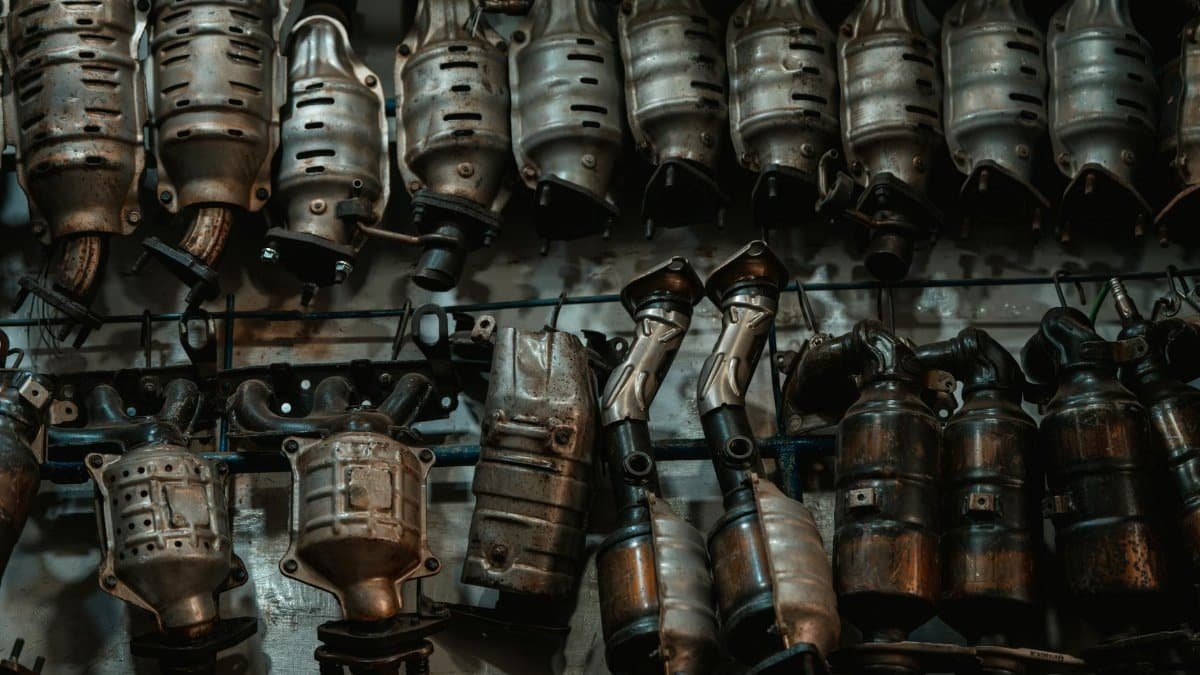 Rows of used catalytic converters in an automotive workshop setting.