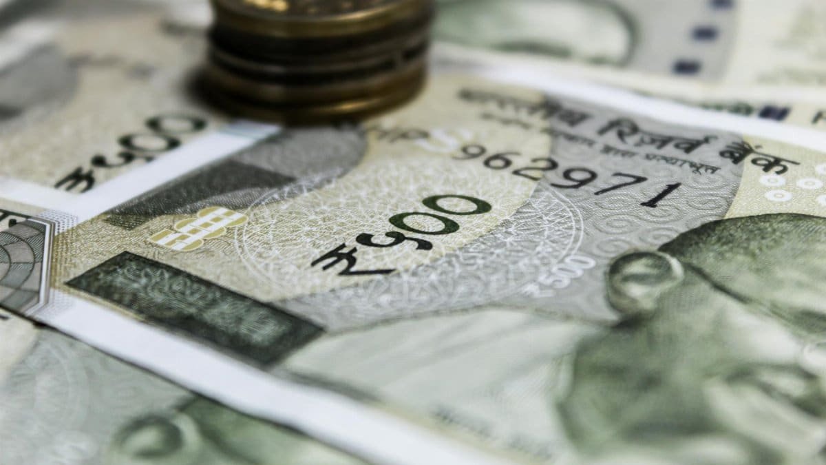 Detailed image of Indian Rupees banknotes with a stack of coins, emphasizing currency details.