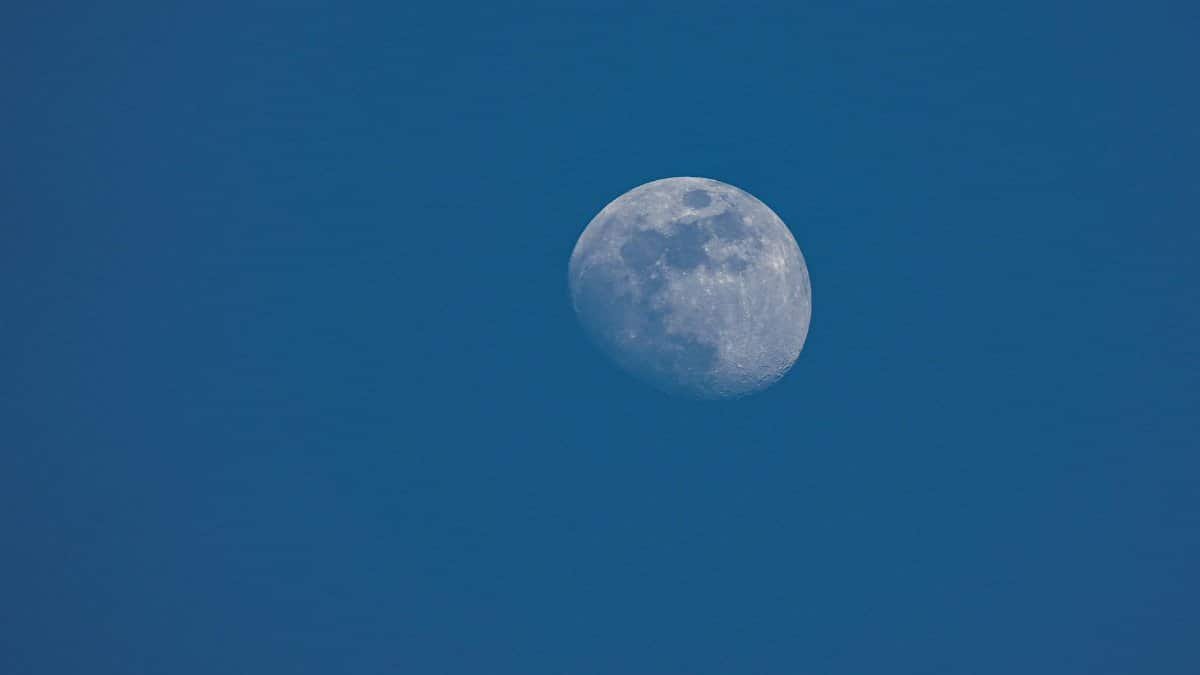 A close-up of the moon against a clear blue sky, captured during the day.