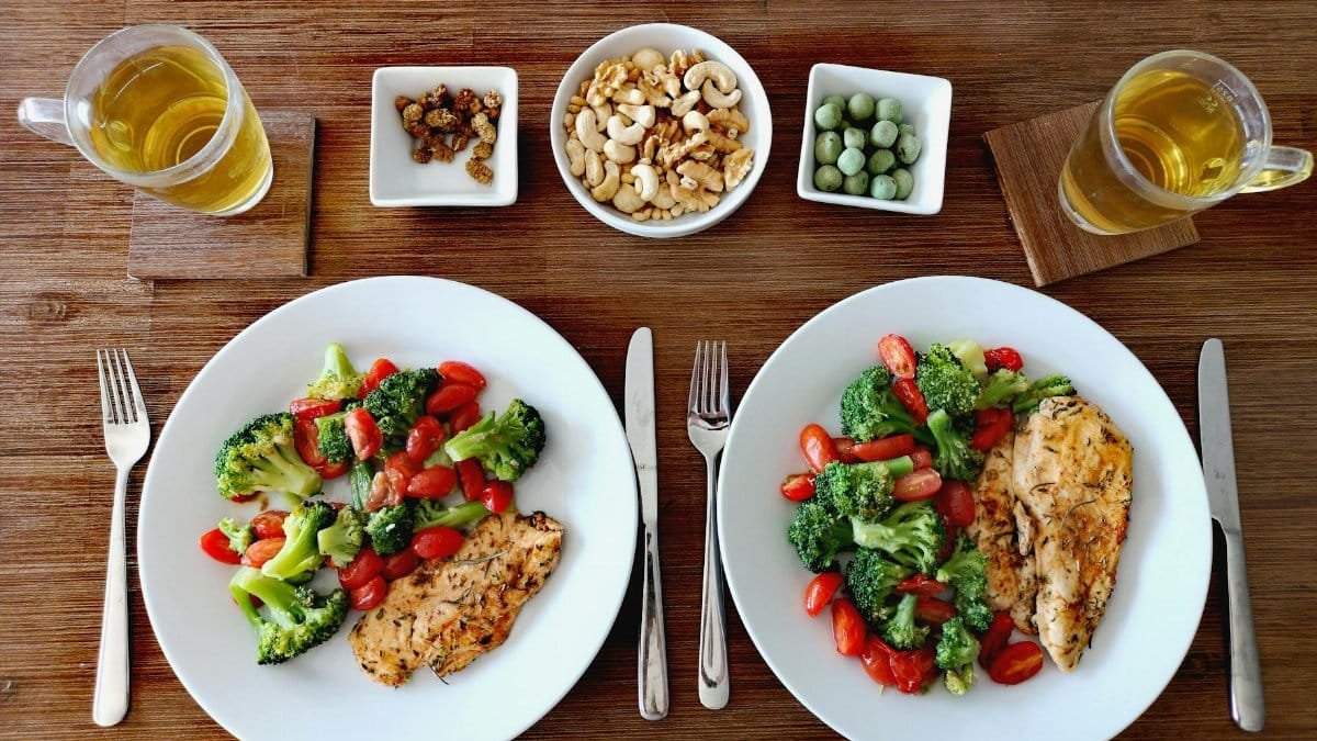 A delicious and healthy chicken dinner with fresh vegetables, nuts, and tea in a cozy setting.