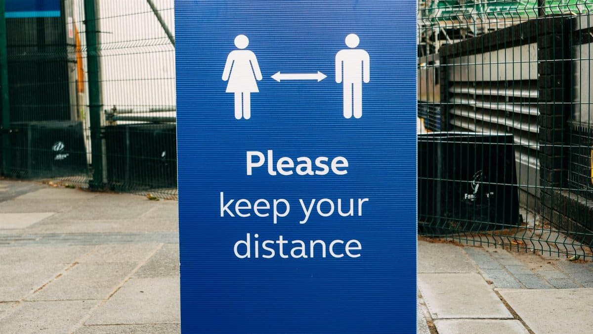 Banner with inscription Please Keep Your Distance and arrow between human figures on street during coronavirus epidemic