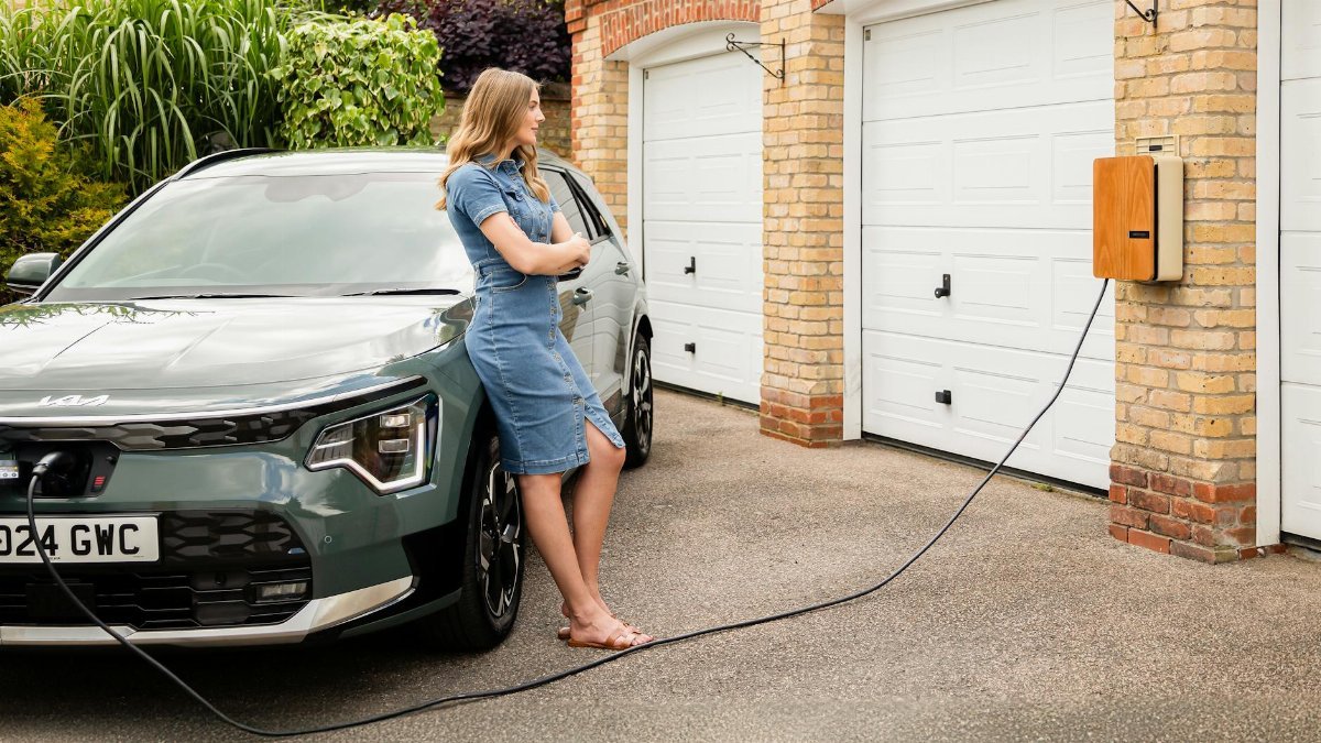 Woman charging electric vehicle at home with a modern wall-mounted charging station.