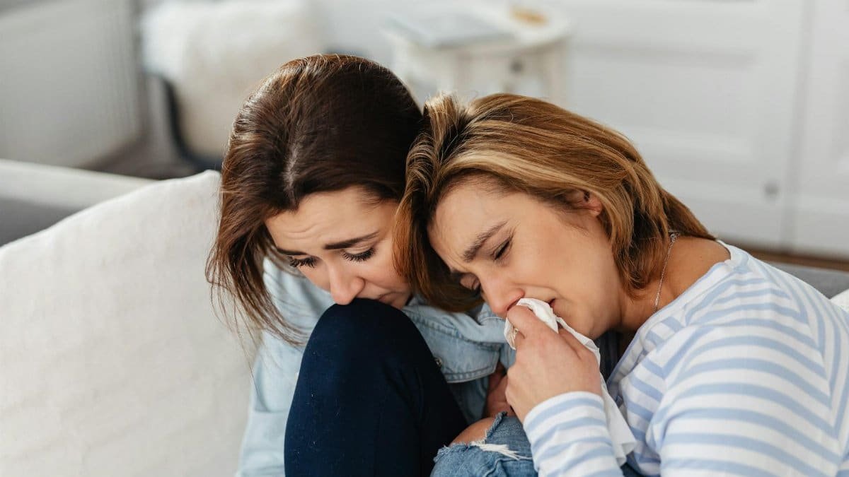 Two women comforting each other while experiencing emotional stress indoors.