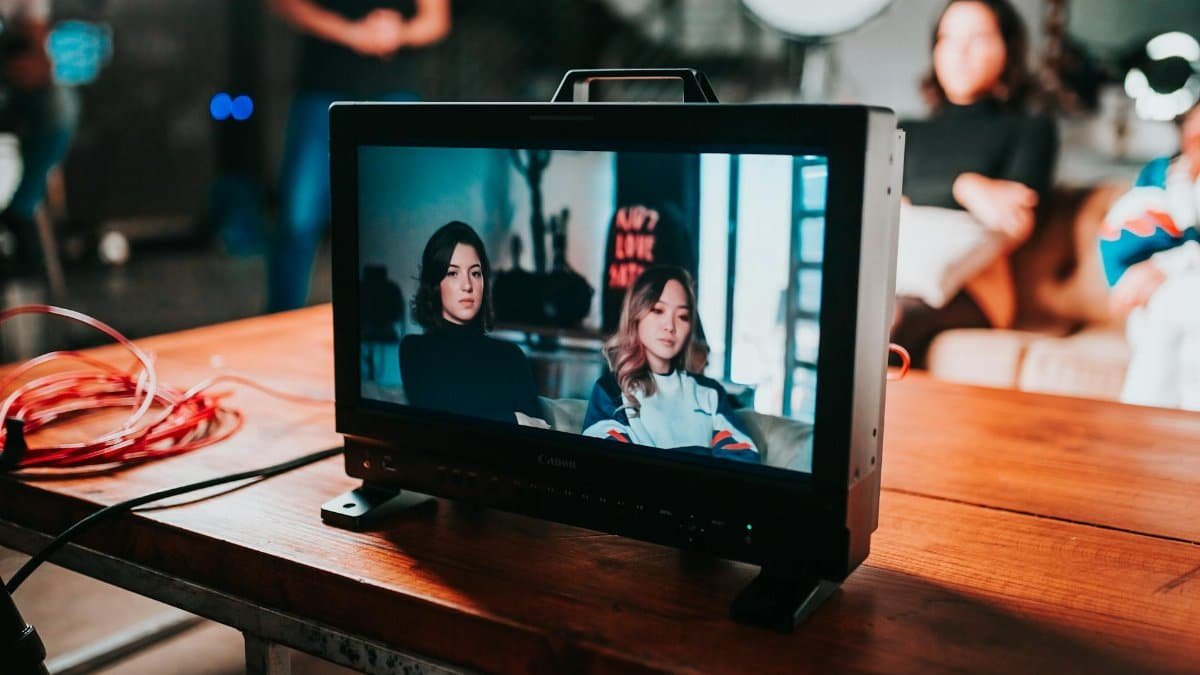 A professional photoshoot setup displaying two women on a monitor in a studio environment.