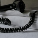 A coiled hair dryer placed on folded white towels, suggesting a hotel setting.