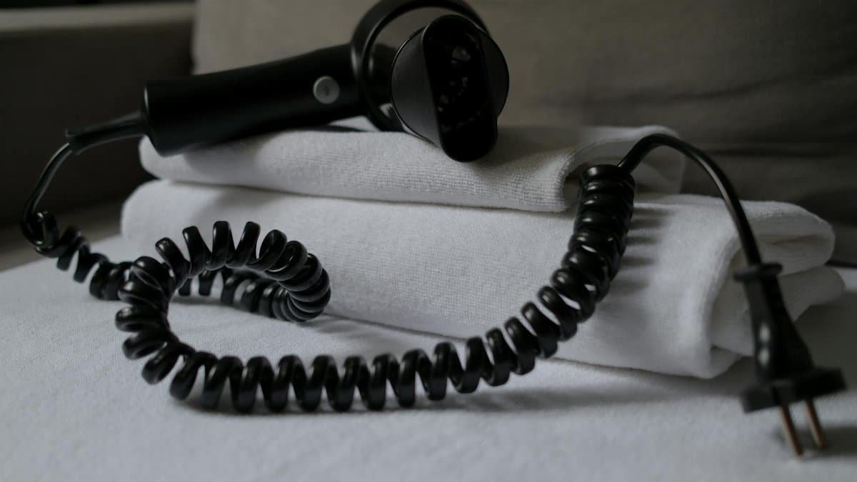 A coiled hair dryer placed on folded white towels, suggesting a hotel setting.