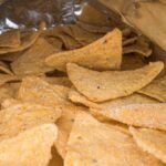 Detailed image of crispy salted corn chips inside an open snack bag.
