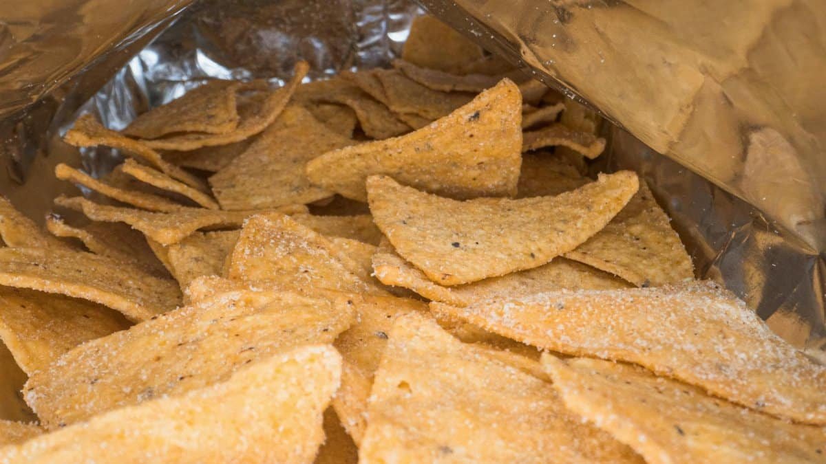 Detailed image of crispy salted corn chips inside an open snack bag.