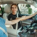 A mother supports her teenage son as he learns to drive in a car